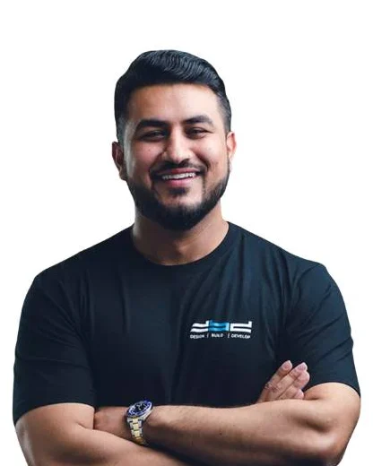 Studio portrait of a smiling man with folded arms, in a shirt carrying the DBD mark.